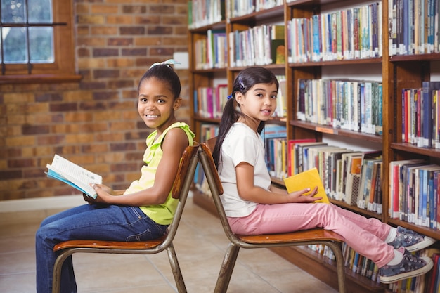 Estudantes sorridentes lendo livros na biblioteca