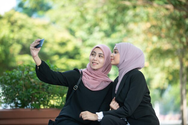 Estudantes tirando selfie com telefone celular contra árvores
