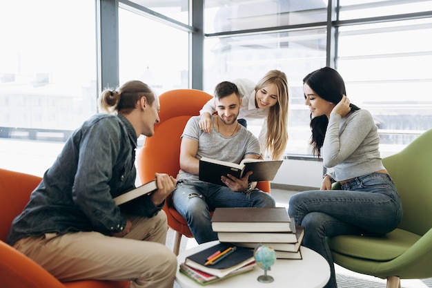 Estudantes trabalham no projeto com livros sentados em uma pequena mesa na biblioteca