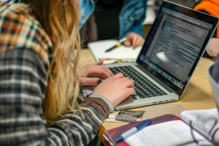 Foto estudantes trabalhando em laptops e fazendo anotações em uma sessão de estudo colaborativo