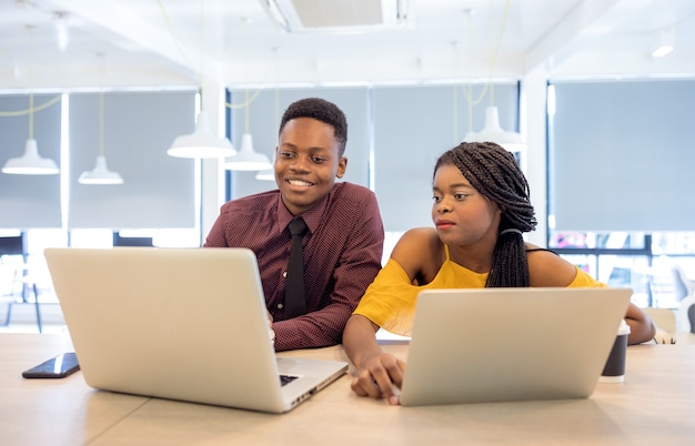 Estudantes universitários africanos usando laptop juntos.