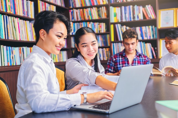 Estudantes universitários asiáticos sentados lendo estudando examinando livros de tutores com amigos