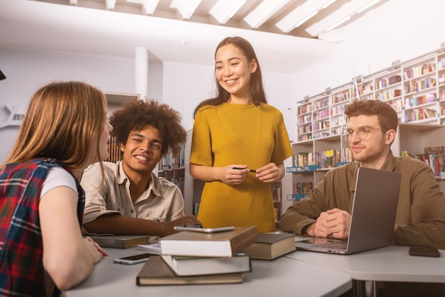 Estudantes universitários estão estudando em uma biblioteca juntos
