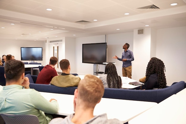 Estudantes universitários estudam em uma sala de aula com professor masculino