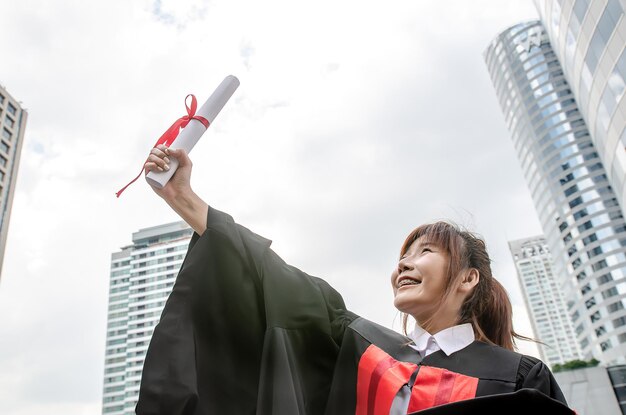 Estudantes universitários felizes mulher asiática segura diploma de graduação