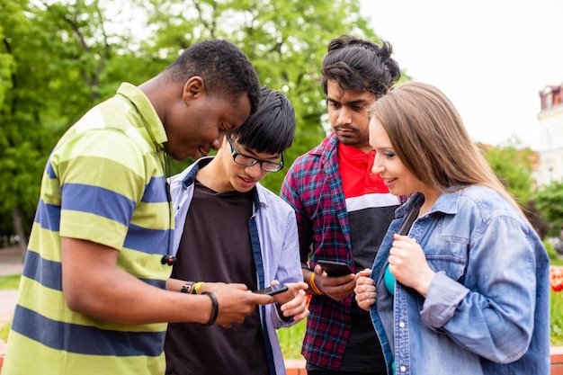Estudantes universitários multiétnicos verificando informações usando telefones celulares