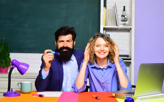 Estudantes universitários na faculdade. casal de estudantes se preparando para teste ou exame. estudantes escolares. dois estudantes sorridentes felizes criativos no auditório. aluna casual feliz com professor hipster barbudo.