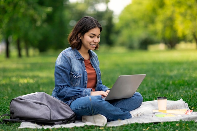 Estudar a distância jovem estudante do Oriente Médio com laptop ao ar livre