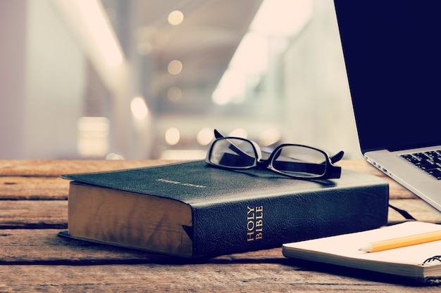 Estude a Bíblia com o laptop na mesa de madeira