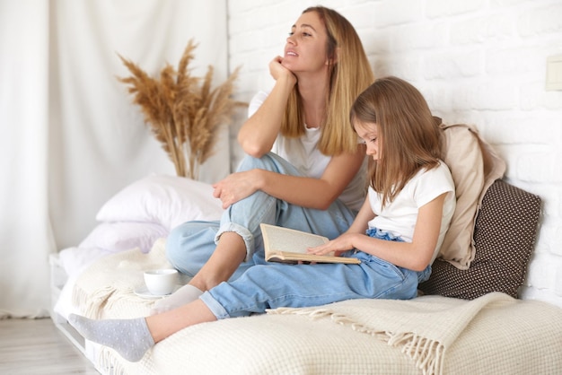 Estude em casa filha e mãe lendo livro na cama em casa