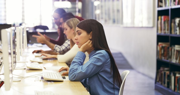 Estudiando para los exámenes finales Captura recortada de estudiantes universitarios que estudian usando las computadoras en la biblioteca del campus