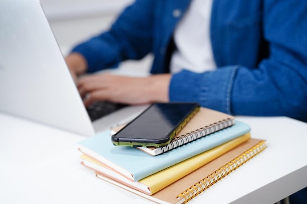 Estudiante adolescente asiático escribe la tarea con una computadora portátil aprendiendo el concepto de educación universitaria