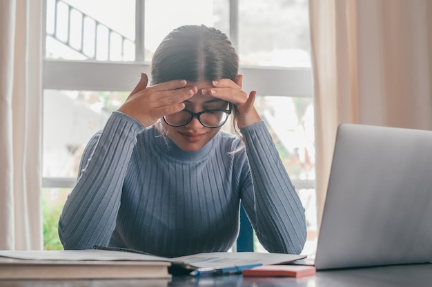 Estudiante adolescente cansada y aburrida que siente dolor de cabeza o fatiga al hacer los deberes en casa Adolescente enferma deprimida y exhausta estudiando sola preocupada por problemas de educación difíciles