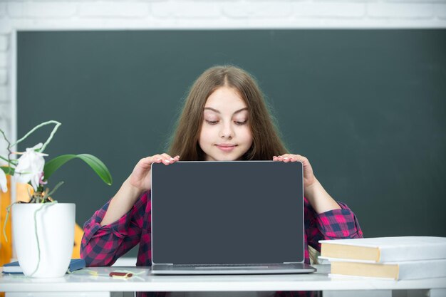 La estudiante adolescente con computadora portátil en la escuela Estudiante adolescente trabajando en la computadora portatil en el aula La niña que usa la computadora portable estudia en línea en la computador Concepto de educación en el hogar Lección escolar