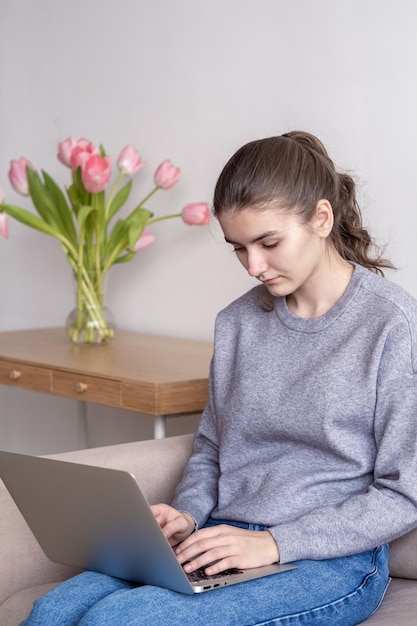 Una estudiante adolescente está trabajando en una computadora portátil en casa