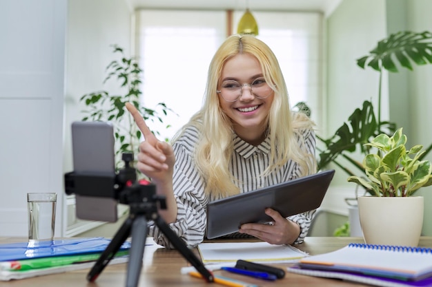 Estudiante adolescente femenina usando tableta digital y teléfono inteligente para estudiar