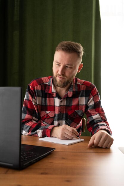 Un estudiante adulto escribe información desde una computadora portátil mientras se prepara para una conferencia en un campus universitario un hipster trabaja en una computadora personal mientras está sentado en un café color vintage