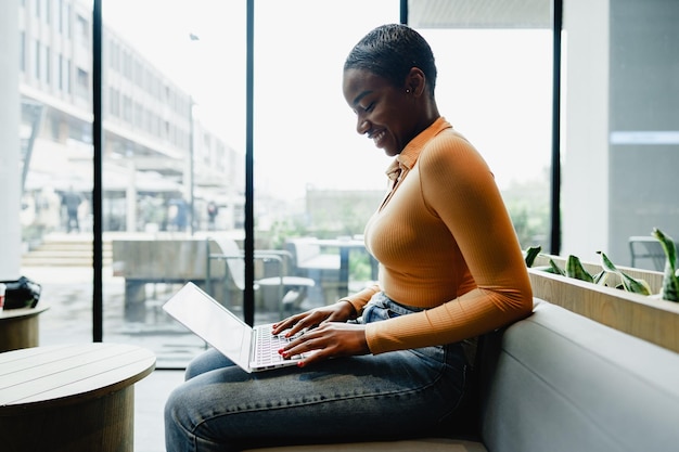 Estudiante africana trabajando en una computadora en un lugar público