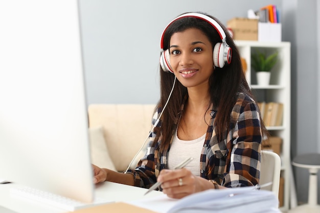 Estudiante africana usa auriculares estudiando sola en el escritorio de la oficina en casa