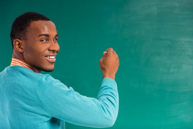 Estudiante africano en una pizarra verde.