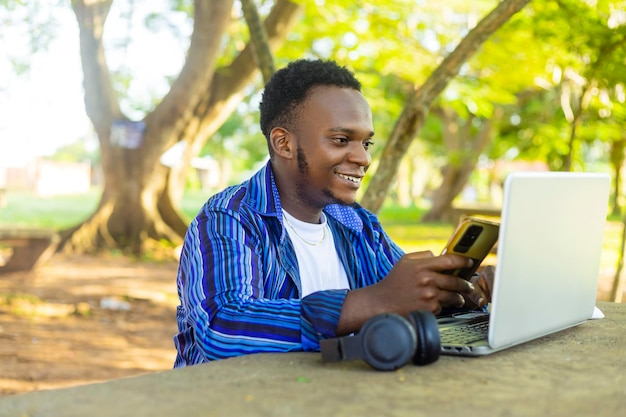 Estudiante afroamericano adolescente guapo negro que usa una computadora portátil para estudiar en línea