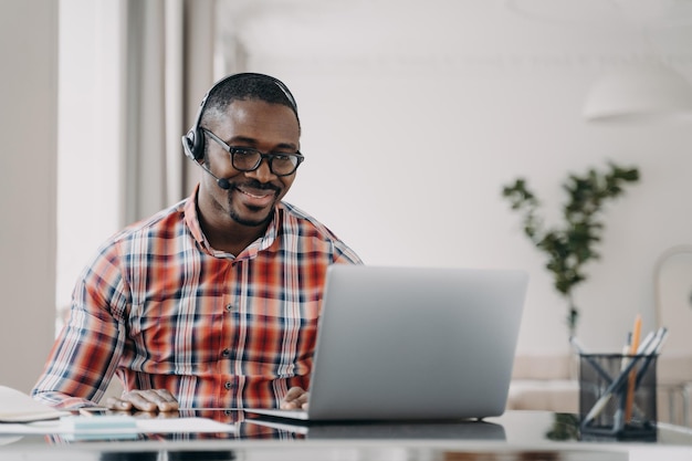 Estudiante afroamericano con auriculares aprende idiomas en línea en una computadora portátil Educación a distancia