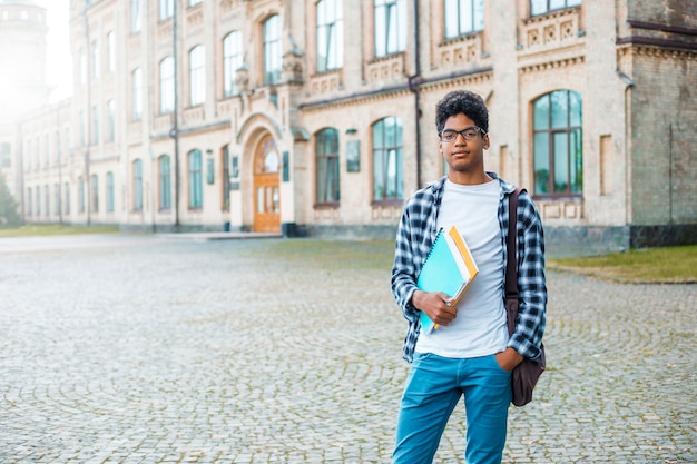 Estudiante afroamericano en vasos con libros.