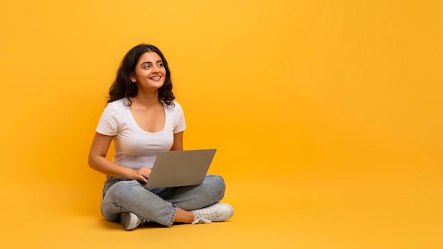 Una estudiante alegre con un cuaderno estudiando en línea