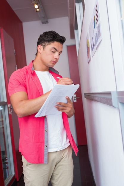 Estudiante alegre de pie tomando notas