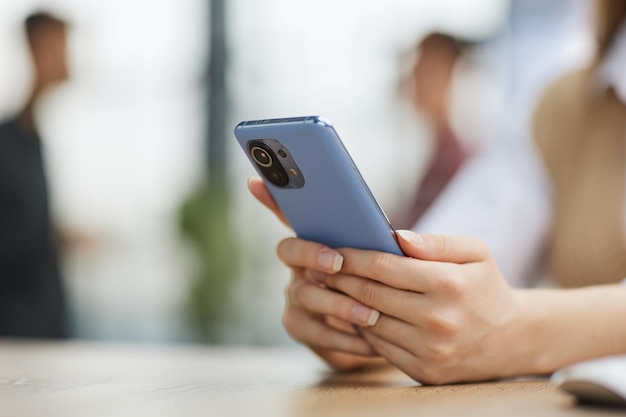 Una estudiante alegre sentada en la mesa con un teléfono móvil recibió un mensaje de un amigo