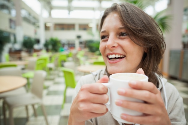 Foto estudiante alegre tomando café en la cafetería