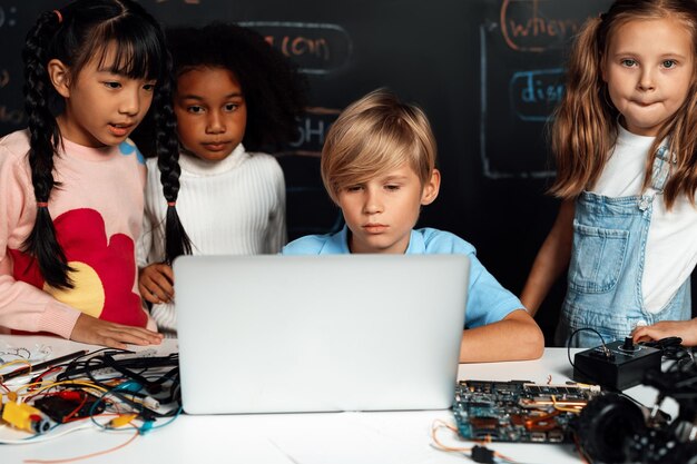 Foto estudiante aprende sobre la codificación de automóviles robóticos en la clase stem con atención erudición