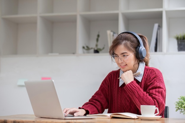 Estudiante asiática estudiando en línea en clase estudiando en Internet con auriculares viendo llamadas de video haciendo zoom mujer asiática feliz aprendiendo idiomas en línea con computadora portátil