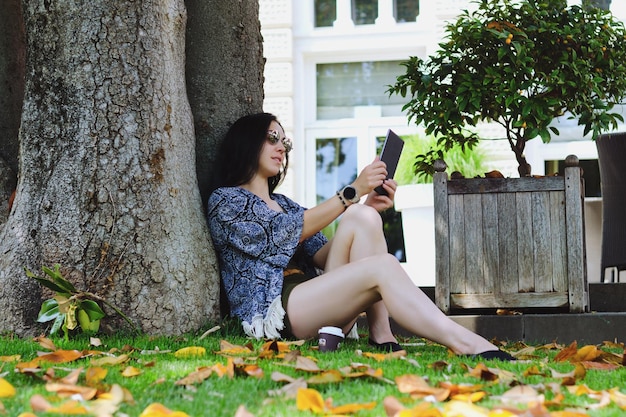 estudiante asiática feliz relajándose trabajando en el jardín botánico de la ciudad usando teléfono portátil redes sociales verano