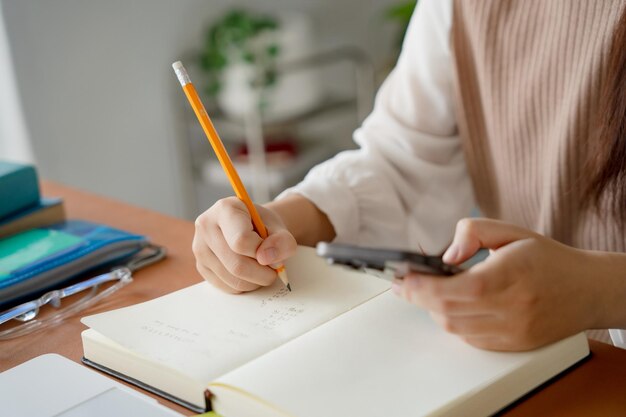 Estudiante asiática haciendo un examen con la mano sosteniendo un lápiz escribiendo una respuesta en la clase universitaria educación estudiante de secundaria o universitaria tomando notas mientras se prepara para el examen