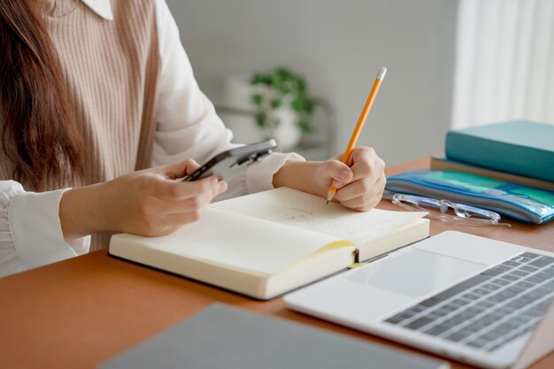 Estudiante asiática haciendo un examen con la mano sosteniendo un lápiz escribiendo una respuesta en la clase universitaria educación estudiante de secundaria o universitaria tomando notas mientras se prepara para el examen