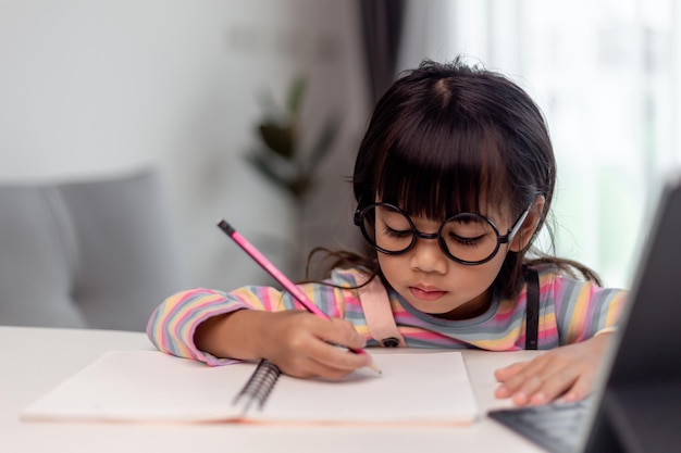 Estudiante asiática en línea clase de aprendizaje estudio en línea con el maestro Niña feliz aprende inglés en línea con tableta en casa Nueva normalidadCovid19 coronavirusDistanciamiento social quedarse en casa