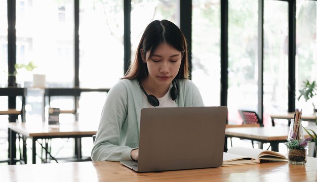 Estudiante asiático enfocado en serio usando una computadora portátil en la cocina mirando la pantalla con atención y concentración viendo un webinar de aprendizaje un curso de video de capacitación virtual estudiando desde casa