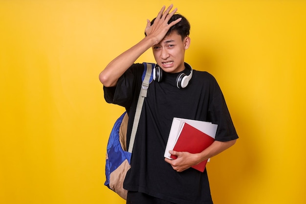 Un estudiante asiático se golpea la cabeza con la mano y tiene un momento duh que olvida algo importante