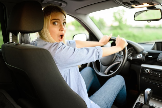 Estudiante asustada en el coche, lección de autoescuela. Hombre enseñando a la señora a conducir un vehículo.