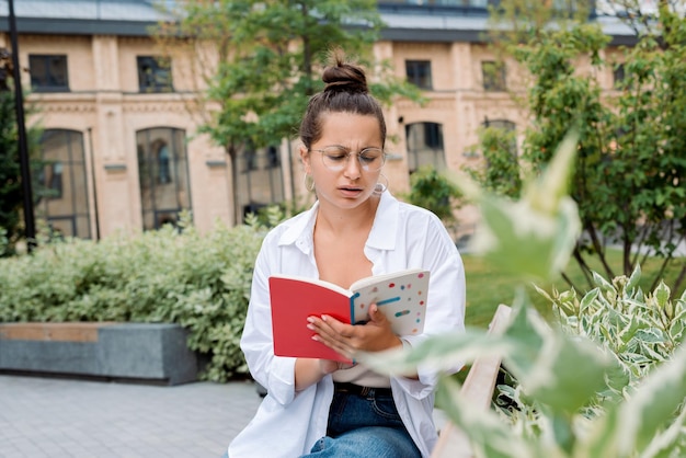 Foto una estudiante atractiva está molesta por leer un libro porque obtuvo una calificación baja en la universidad