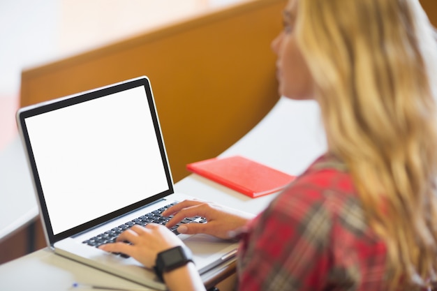 Estudiante atractivo que usa el ordenador portátil en sala de conferencias