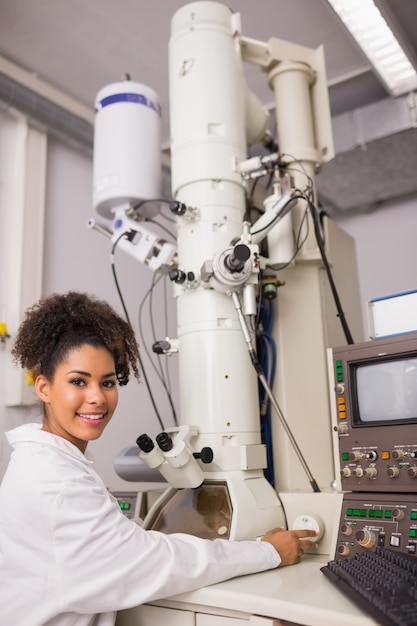 Estudiante de bioquímica con gran microscopio y computadora