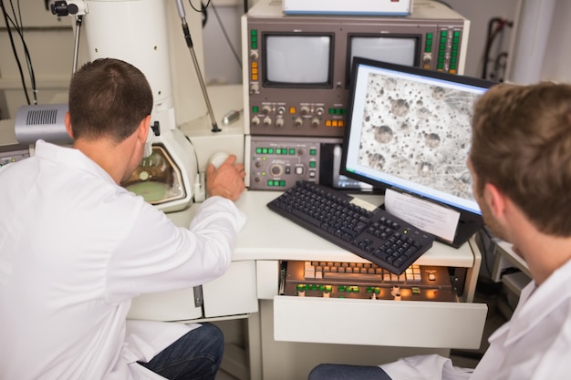 Foto estudiante de bioquímica con gran microscopio y computadora