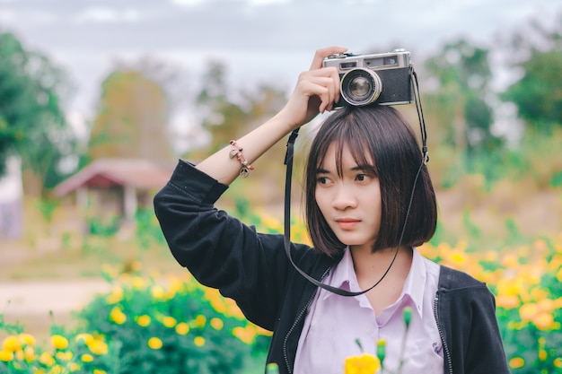 Estudiante con cámara vintage en el jardín de flores.