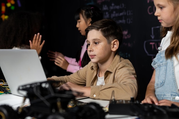Estudiante de camisa marrón y estudiante de babero blanco miran la computadora portátil y discuten erudición