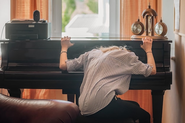 Una estudiante cansada y molesta se encuentra en la cubierta del piano y no quiere hacer música