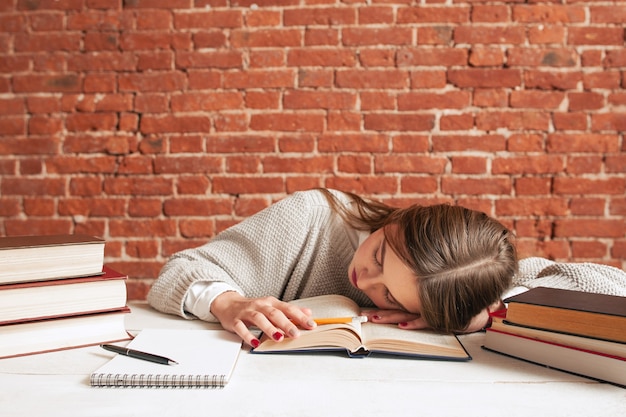 Estudiante cansado durmiendo en el libro en la biblioteca