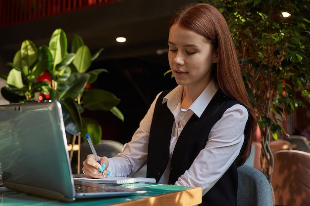 Estudiante caucásico sentado en la mesa del café estudiando con una laptop haciendo la tarea