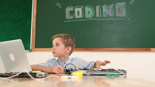 Estudiante caucásico trabajando en una tabla electrónica mientras está sentado en la clase de pedagogía